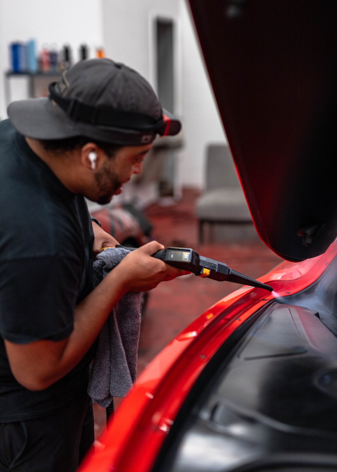Obsidian detailer machine-polishing a red supercar at a Durham location